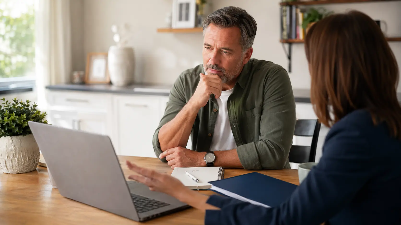 A man discussing his finances with an advisor while deciding whether to borrow from whole life insurance.